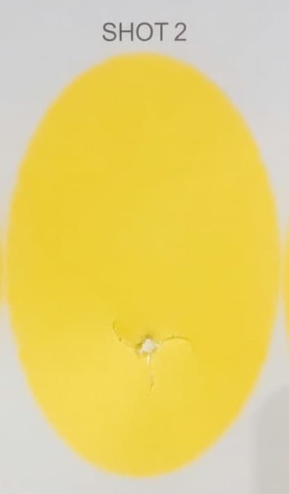 Clean bullet-hole tear through a paper tuning target